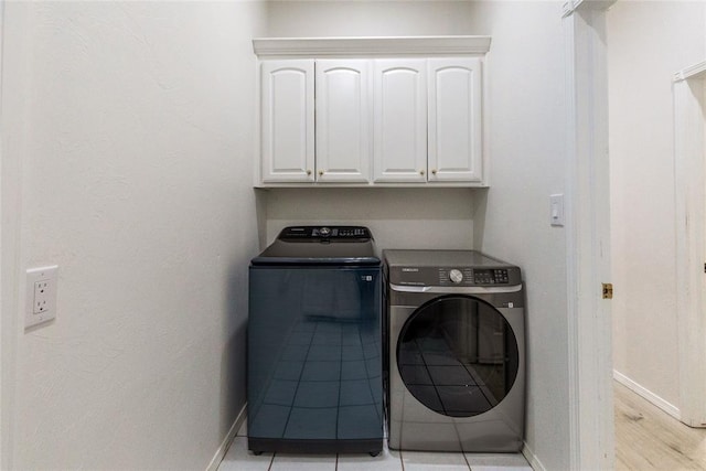laundry room featuring separate washer and dryer, baseboards, and cabinet space
