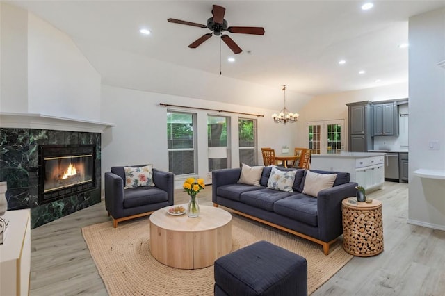 2617 Tracys Ter, Edmond, OK 73013 - living room featuring vaulted ceiling, light wood finished floors, a high end fireplace, ceiling fan, and a chandelier