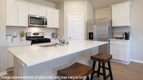 10509 SW 23rd St, Yukon, OK 73099 - kitchen featuring stainless steel appliances, baseboards, white cabinetry, a sink, and a kitchen island with sink