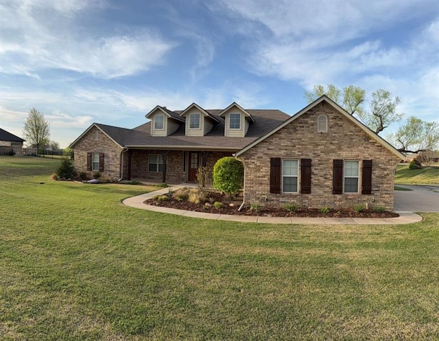 view of front of home featuring brick siding, a front lawn, and a shingled roof