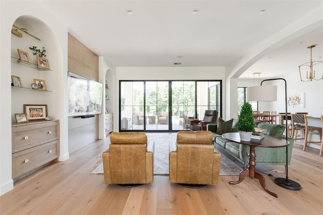 living area featuring light wood-style flooring and arched walkways