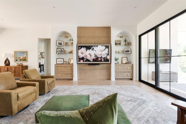 living area featuring light wood-type flooring and built in shelves