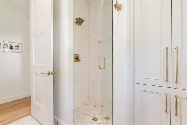 bathroom with a shower stall, baseboards, and wood finished floors