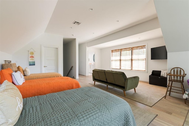 bedroom with light wood finished floors and lofted ceiling