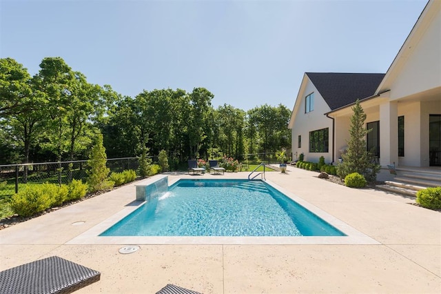 view of swimming pool with a patio area, fence, and view of wooded area