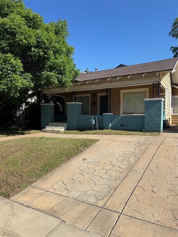 view of front of property featuring roof with shingles, brick siding, and a front lawn