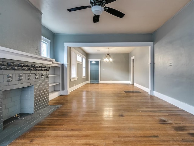 unfurnished living room with a chandelier, wood finished floors, ceiling fan, baseboards, and ornamental molding