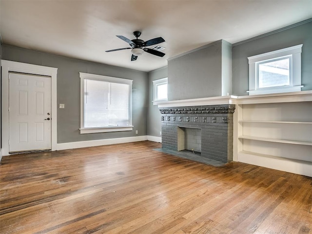 unfurnished living room featuring wood finished floors, a brick fireplace, a ceiling fan, and baseboards