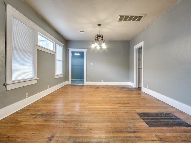unfurnished dining area featuring a chandelier, light wood-type flooring, and baseboards