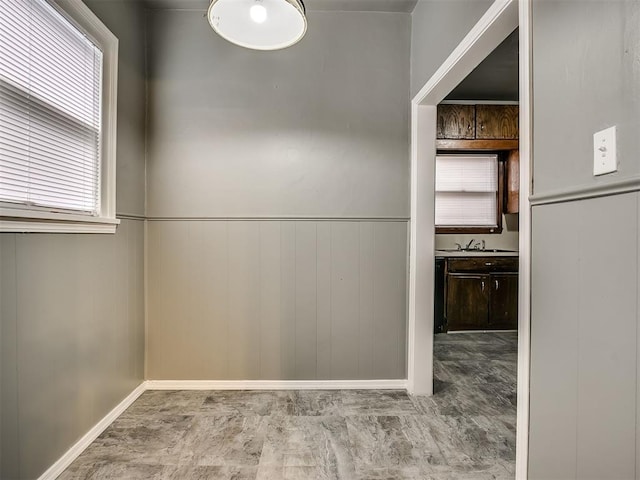 unfurnished dining area featuring a sink, wainscoting, and baseboards