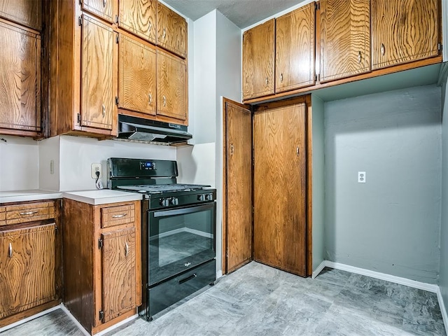 kitchen featuring gas stove, under cabinet range hood, light countertops, brown cabinetry, and baseboards