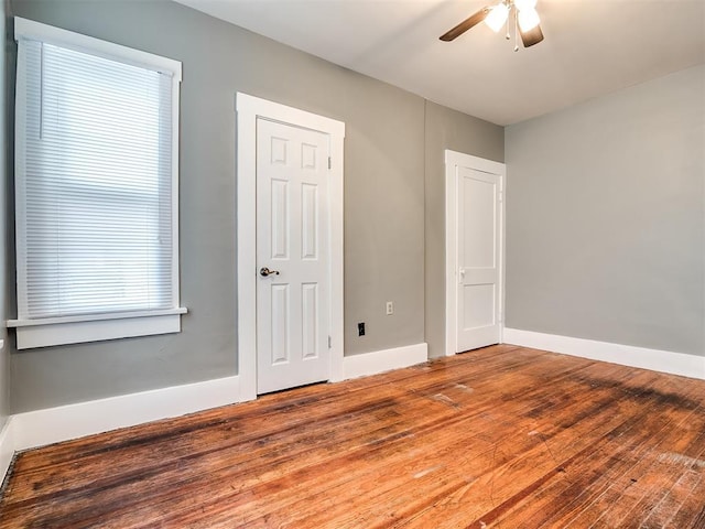 unfurnished bedroom featuring wood finished floors, baseboards, and a ceiling fan