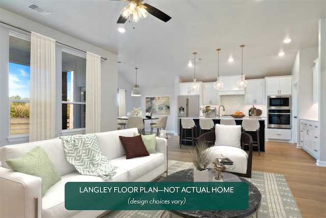 living room with a ceiling fan, light wood-style flooring, and lofted ceiling