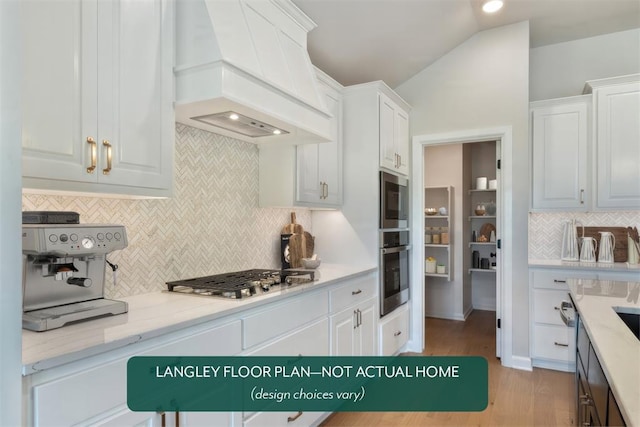 kitchen with custom exhaust hood, appliances with stainless steel finishes, decorative backsplash, lofted ceiling, and white cabinets