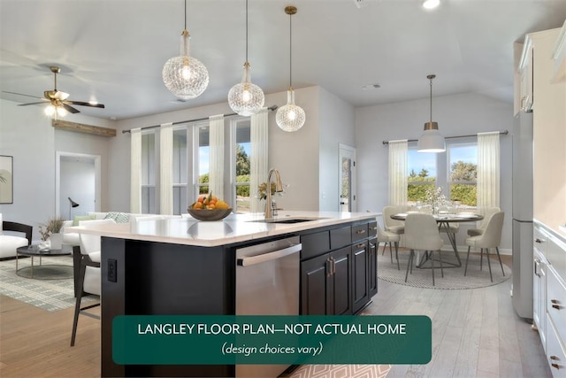 kitchen with a sink, stainless steel dishwasher, light countertops, light wood-style flooring, and lofted ceiling