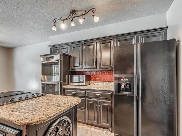 1409 Echohollow Trl, Edmond, OK 73025 - kitchen featuring black appliances, a textured ceiling, light tile patterned flooring, dark brown cabinetry, and a center island