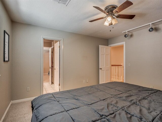 1409 Echohollow Trl, Edmond, OK 73025 - carpeted bedroom featuring baseboards, a textured ceiling, ensuite bath, and a ceiling fan