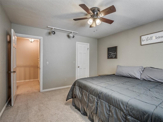 1409 Echohollow Trl, Edmond, OK 73025 - bedroom featuring light carpet, a textured ceiling, a ceiling fan, and baseboards