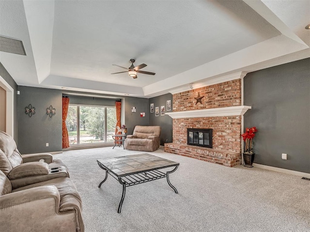 1409 Echohollow Trl, Edmond, OK 73025 - carpeted living room with a tray ceiling, ceiling fan, and a fireplace