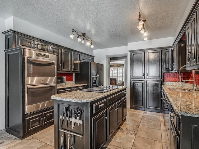 1409 Echohollow Trl, Edmond, OK 73025 - kitchen featuring stainless steel double oven, black fridge, cooktop, a kitchen island, and dark cabinetry