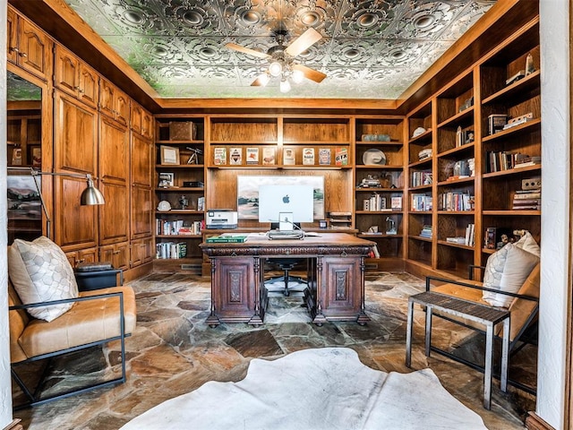 home office featuring ceiling fan, dark stone finish floors, an ornate ceiling, and built in features