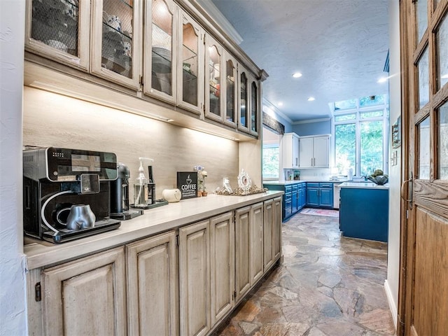 kitchen featuring light stone finish floors, light countertops, glass insert cabinets, crown molding, and recessed lighting