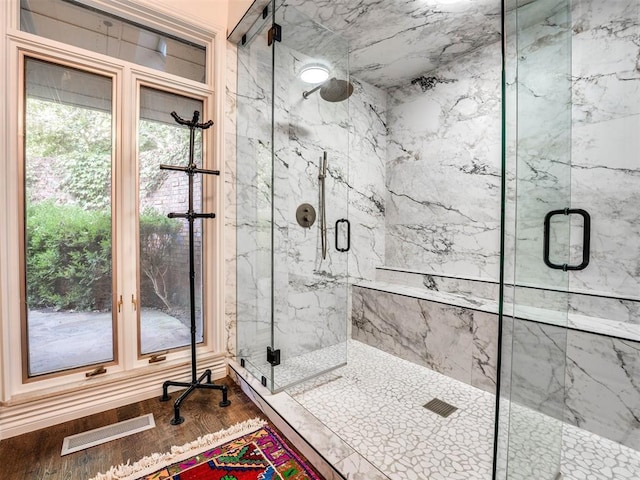 bathroom with a marble finish shower and wood finished floors