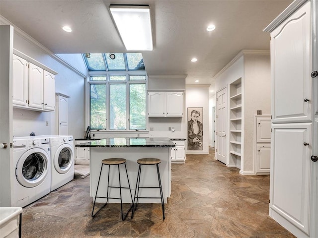clothes washing area featuring washing machine and clothes dryer, crown molding, stone finish floors, recessed lighting, and a skylight