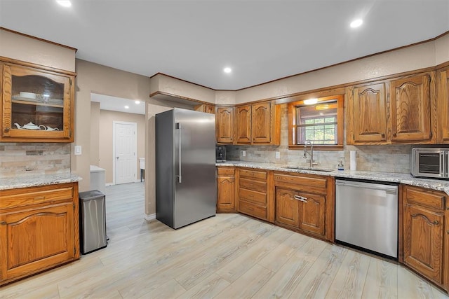 11747 N 2240th Rd, Cordell, OK 73632 - kitchen featuring appliances with stainless steel finishes, a sink, brown cabinets, tasteful backsplash, and light wood-style flooring