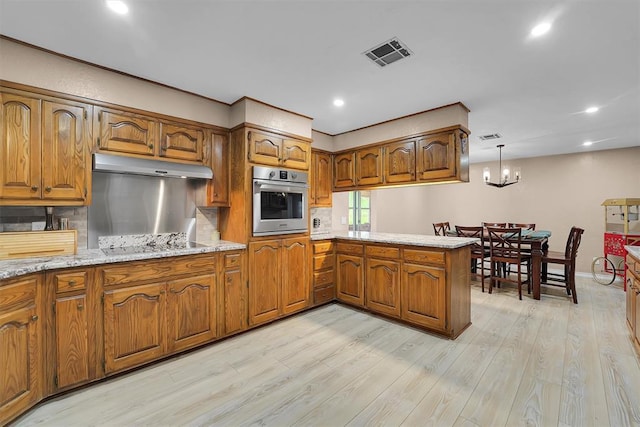 11747 N 2240th Rd, Cordell, OK 73632 - kitchen featuring oven, brown cabinetry, under cabinet range hood, a peninsula, and recessed lighting