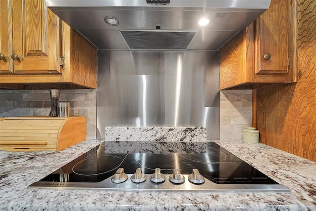 11747 N 2240th Rd, Cordell, OK 73632 - kitchen with under cabinet range hood, black electric cooktop, brown cabinets, and decorative backsplash
