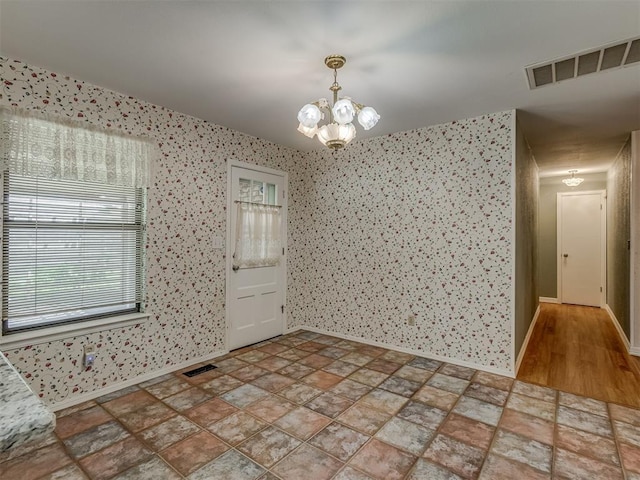 8709 NW 86th St, Oklahoma City, OK 73132 - empty room with baseboards, wallpapered walls, a chandelier, and stone finish floors
