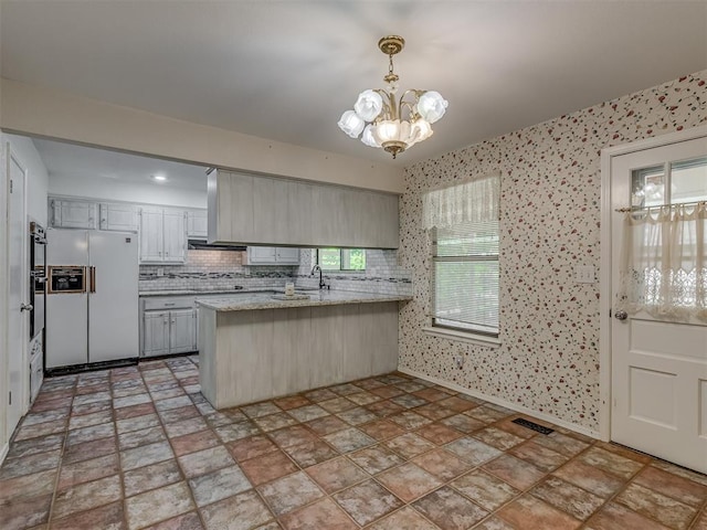 8709 NW 86th St, Oklahoma City, OK 73132 - kitchen with white fridge with ice dispenser, a peninsula, a chandelier, backsplash, and hanging light fixtures