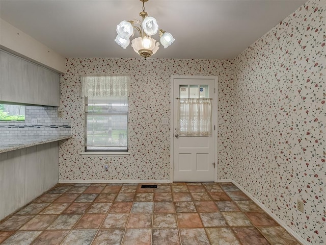 8709 NW 86th St, Oklahoma City, OK 73132 - unfurnished dining area with a chandelier, baseboards, stone finish flooring, and wallpapered walls