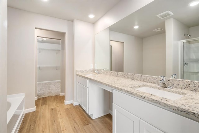 5450 Mac Rd, Tuttle, OK 73089 - bathroom featuring a shower stall, wood finished floors, double vanity, a bath, and a spacious closet