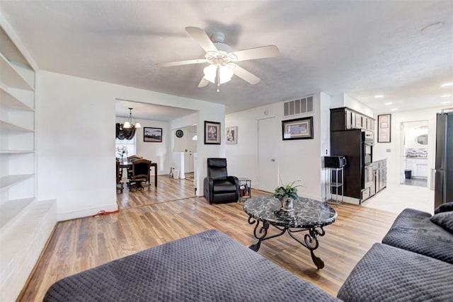6508 S Harvey Ave, Oklahoma City, OK 73139 - living area featuring a chandelier, a ceiling fan, light wood-style floors, and built in shelves