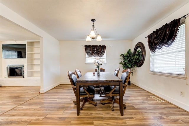 6508 S Harvey Ave, Oklahoma City, OK 73139 - dining room with baseboards, light wood-style floors, built in features, and a glass covered fireplace