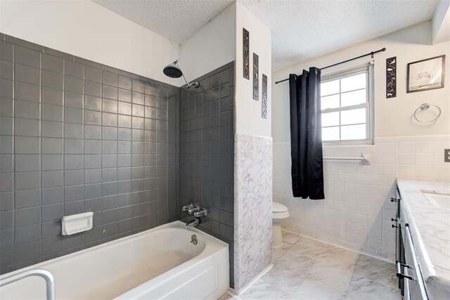 6508 S Harvey Ave, Oklahoma City, OK 73139 - bathroom with a textured ceiling, toilet, vanity, bathtub / shower combination, and tile walls