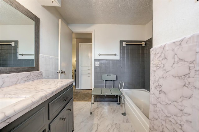 6508 S Harvey Ave, Oklahoma City, OK 73139 - full bathroom featuring tile walls, a textured ceiling, vanity, marble finish flooring, and a wainscoted wall
