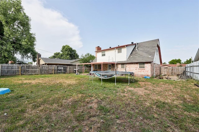 6508 S Harvey Ave, Oklahoma City, OK 73139 - rear view of house featuring a trampoline, brick siding, and a chimney