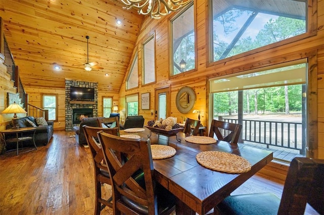 479 Poplar Cir, Broken Bow, OK 74728 - dining room with hardwood / wood-style flooring, wood walls, high vaulted ceiling, a chandelier, and a fireplace