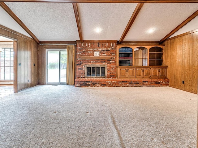 10021 Henderson Dr, Oklahoma City, OK 73139 - unfurnished living room featuring a textured ceiling, wooden walls, carpet flooring, and a fireplace