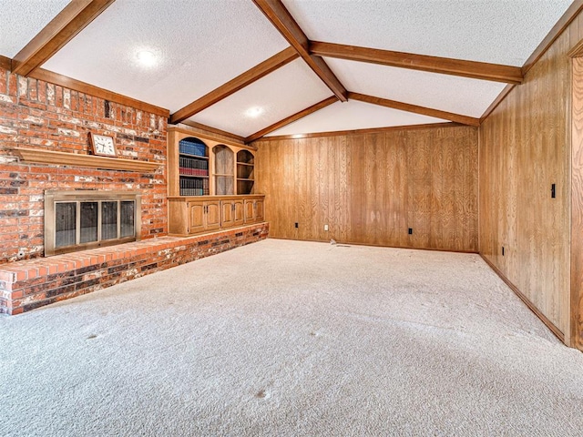 10021 Henderson Dr, Oklahoma City, OK 73139 - unfurnished living room with a textured ceiling, wood walls, carpet floors, and a brick fireplace