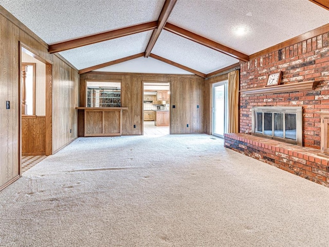 10021 Henderson Dr, Oklahoma City, OK 73139 - unfurnished living room featuring a textured ceiling, wooden walls, a brick fireplace, plenty of natural light, and carpet