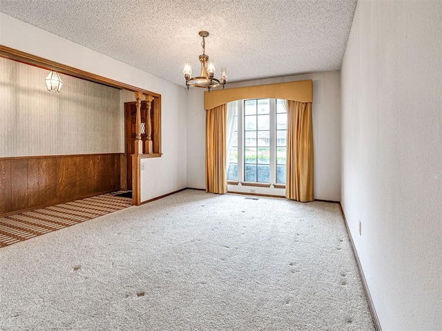 10021 Henderson Dr, Oklahoma City, OK 73139 - carpeted spare room featuring a chandelier, wooden walls, and a textured ceiling