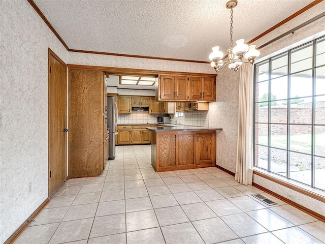 10021 Henderson Dr, Oklahoma City, OK 73139 - kitchen with ornamental molding, a textured ceiling, a peninsula, brown cabinetry, and a chandelier