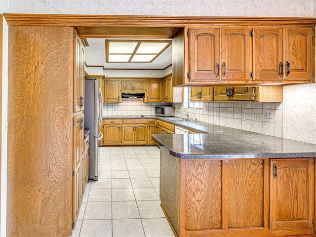 10021 Henderson Dr, Oklahoma City, OK 73139 - kitchen with stainless steel appliances, a peninsula, brown cabinetry, a sink, and tasteful backsplash