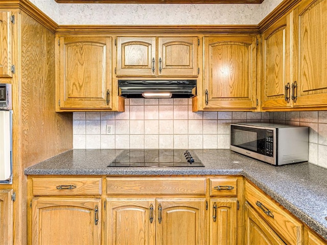 10021 Henderson Dr, Oklahoma City, OK 73139 - kitchen featuring black electric cooktop, under cabinet range hood, dark countertops, tasteful backsplash, and brown cabinets