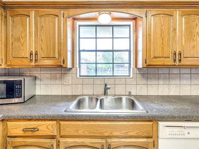 10021 Henderson Dr, Oklahoma City, OK 73139 - kitchen featuring stainless steel microwave, a sink, white dishwasher, dark countertops, and decorative backsplash