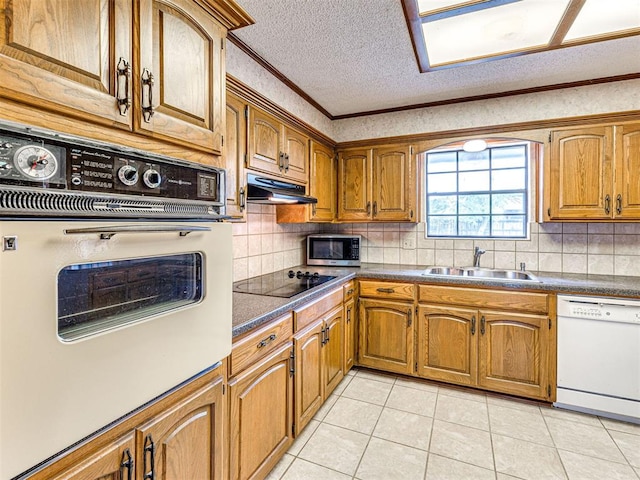 10021 Henderson Dr, Oklahoma City, OK 73139 - kitchen featuring white appliances, a sink, under cabinet range hood, dark countertops, and brown cabinets